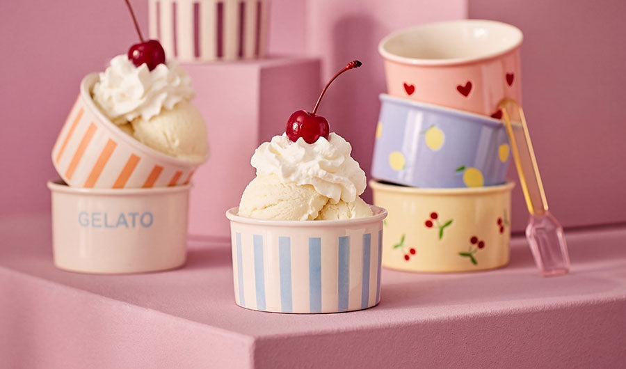 Pastellfarbene Gelato-Schalen mit Vanilleeis und Kirschen