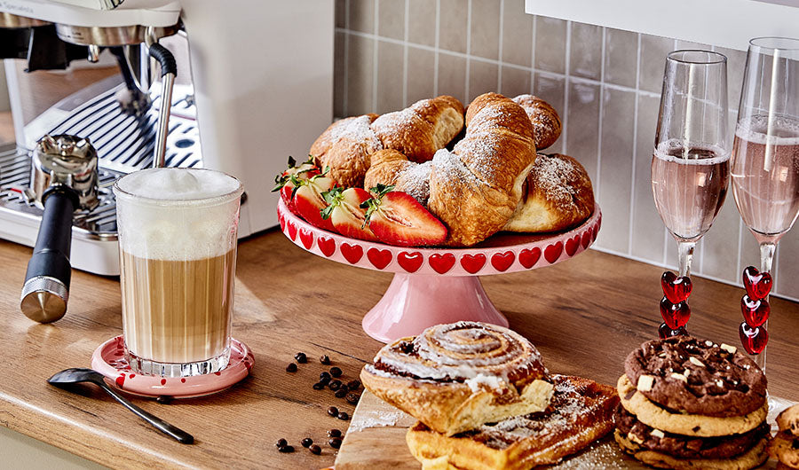 Rosafarbene Etagere mit Croissants Erdbeeren und Café Latte