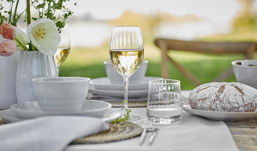Weinglas mit Weißwein auf gedecktem Tisch im Freien