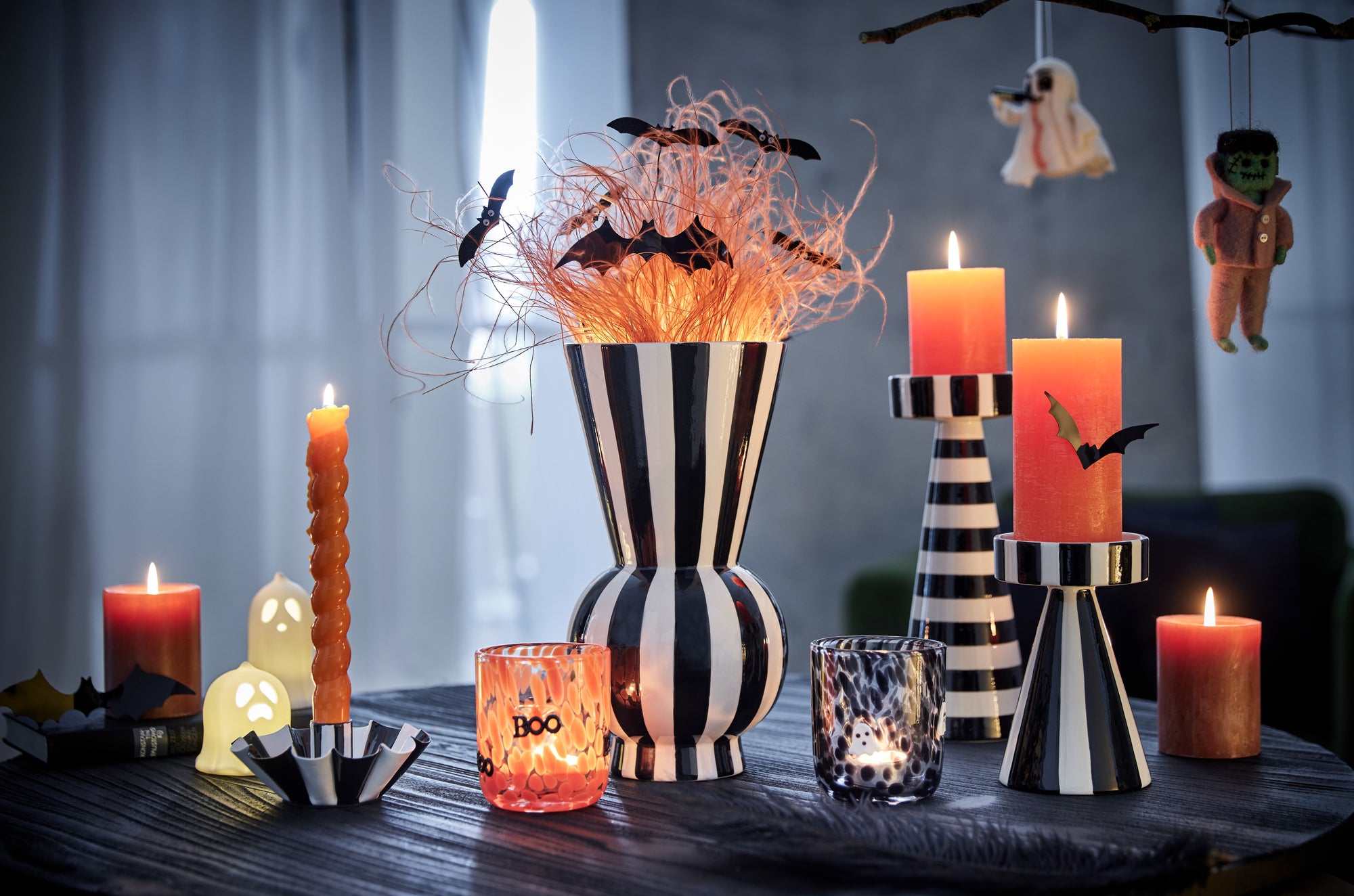 Halloween-Deko mit gestreifter Vase, Kerzen und Fledermäusen