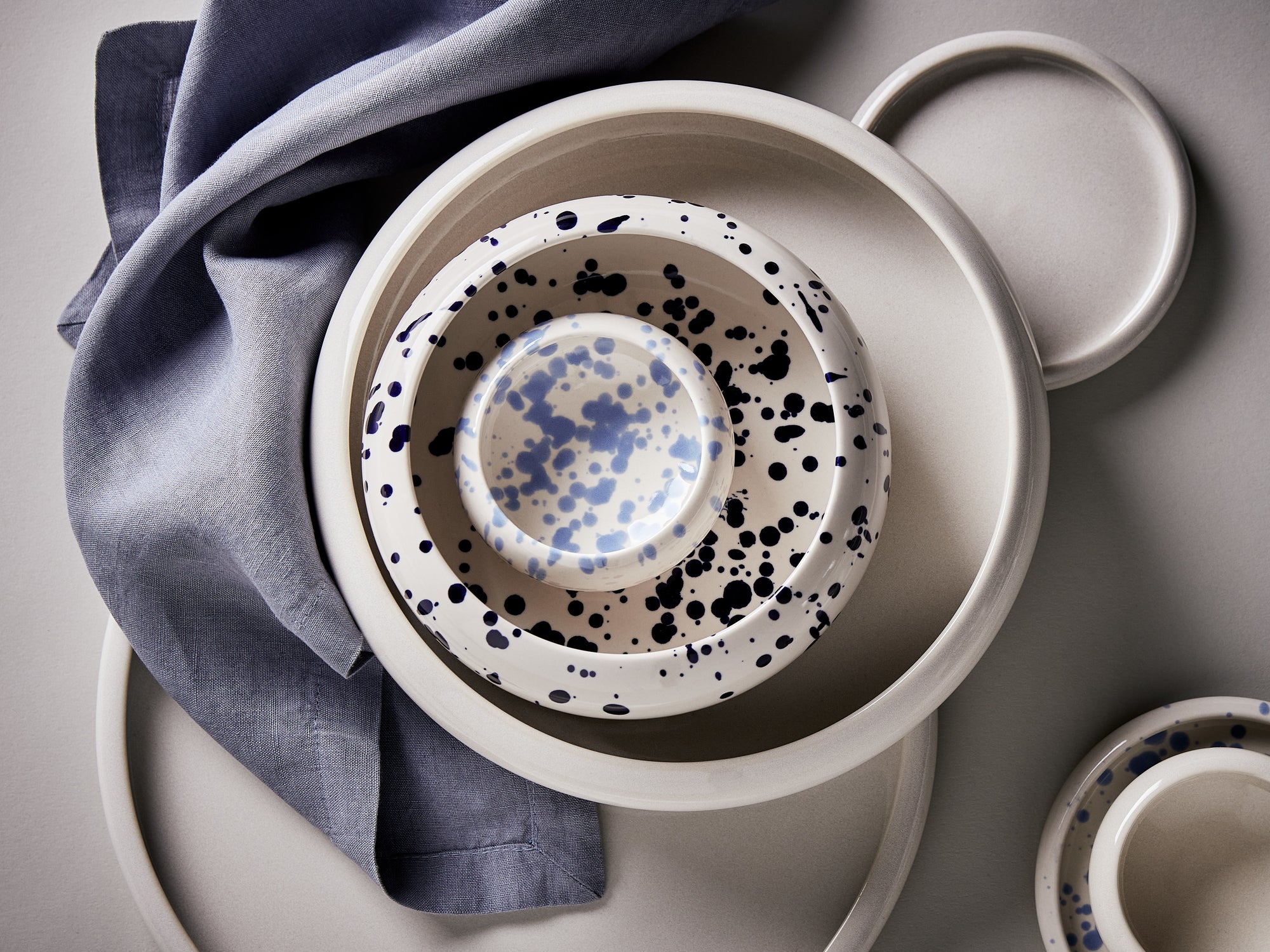 Verschieden große Schüsseln und eine kleine Dipschale aus Keramik mit blauem Punkt-Dekor in der Draufsicht arrangiert.