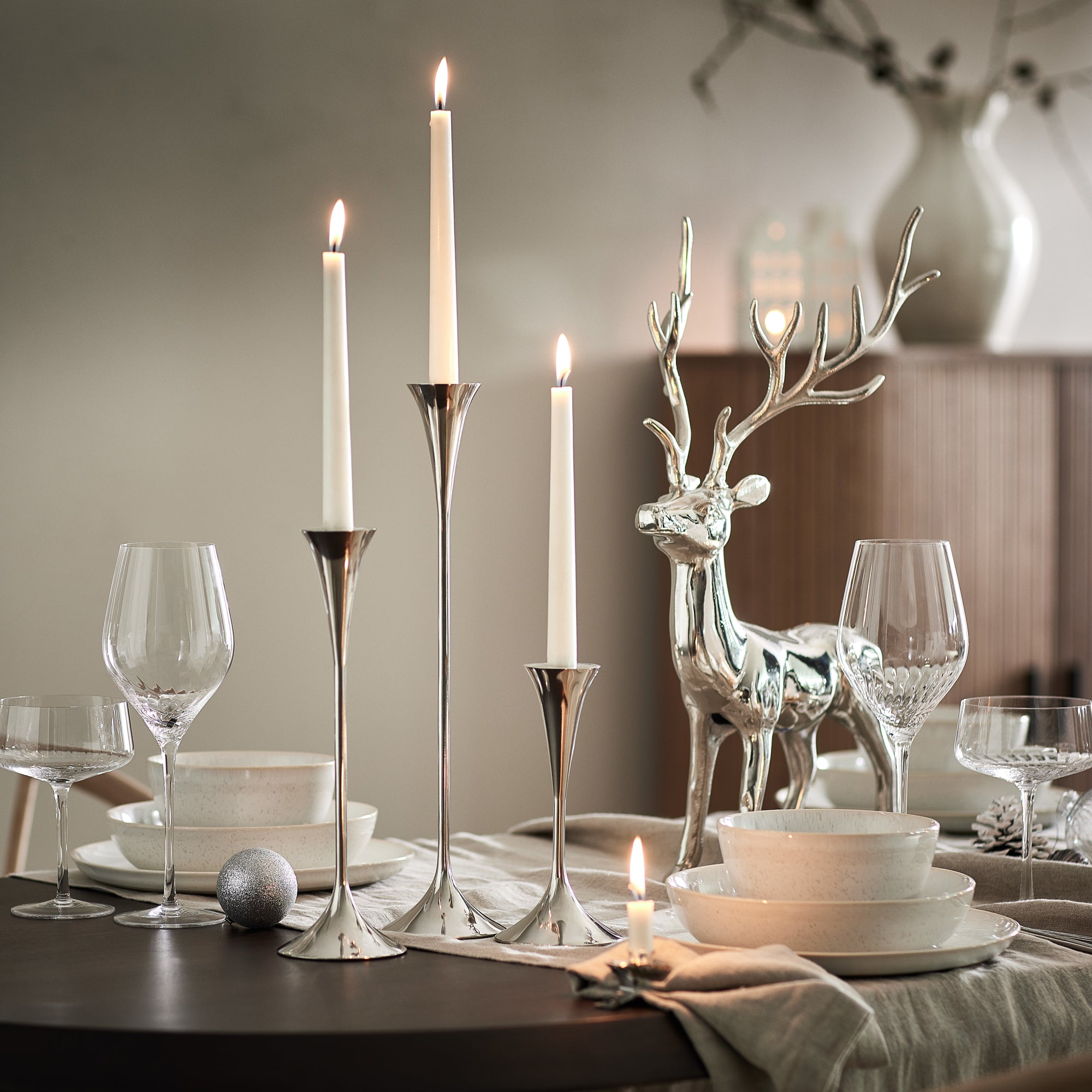 Festlich gedeckter Tisch mit silbernen Kerzenständern und Hirsch