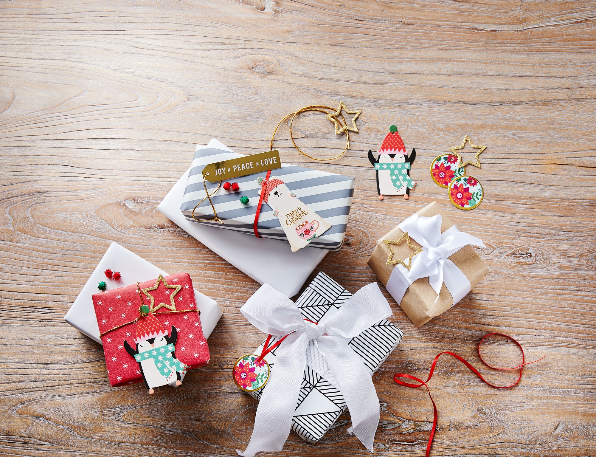 Bunt verpackte Weihnachtsgeschenke mit Anhängern und Deko auf Holztisch